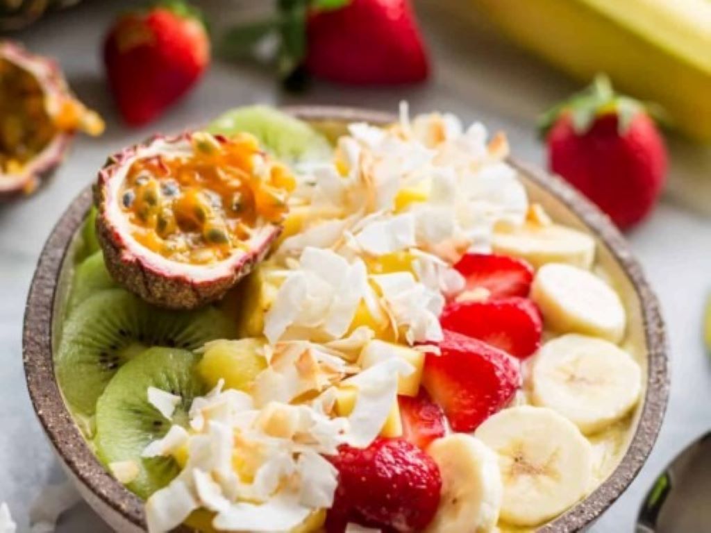Tropical smoothie bowl topped with coconut flakes, pineapple chunks, and Yoplait yogurt swirl