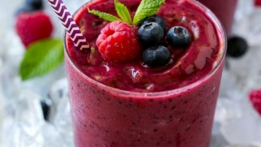 Colorful berry smoothie made with Yoplait yogurt in a tall glass with fresh berries as garnish