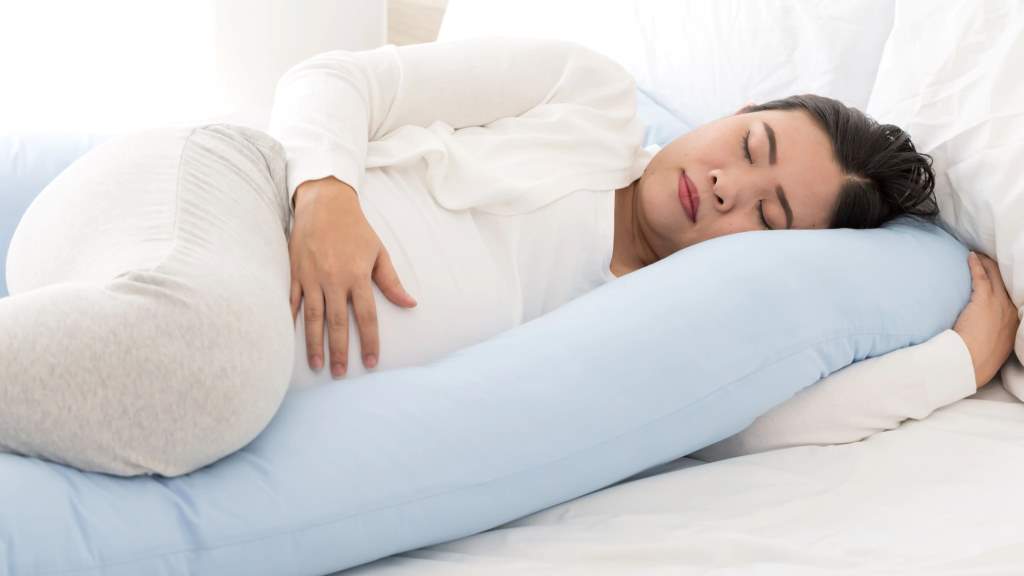 Mom comfortably side-lying breastfeeding newborn post cesarean with supportive pillows