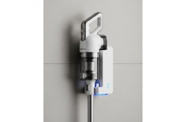 Lightweight cordless stick vacuum standing upright in compact wall-mounted charging dock