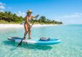 Paddler on an inflatable SUP board in calm Florida coastal waters.